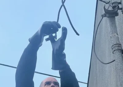 Person wearing gloves working on wires outdoors.