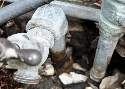 Close-up of a weathered outdoor water faucet with visible rust and corrosion.
