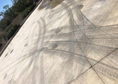 Tire tracks on a concrete surface, likely from skidding or rapid acceleration. Gray and black marks.