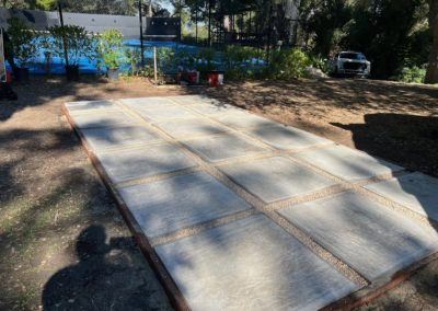 Concrete patio with gravel lines, in a yard near a pool.