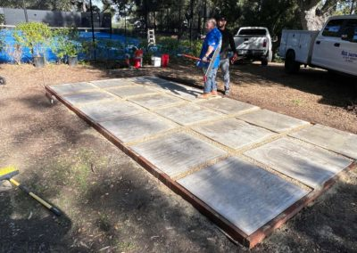 Two men standing on a rectangular platform made of concrete tiles in an outdoor setting.