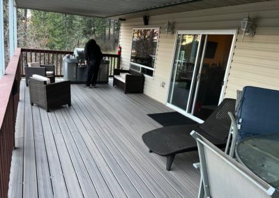 Deck with grill, person, and outdoor furniture. Sliding glass door and covered area.