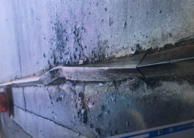 Damaged concrete curb with crumbling edges and debris.