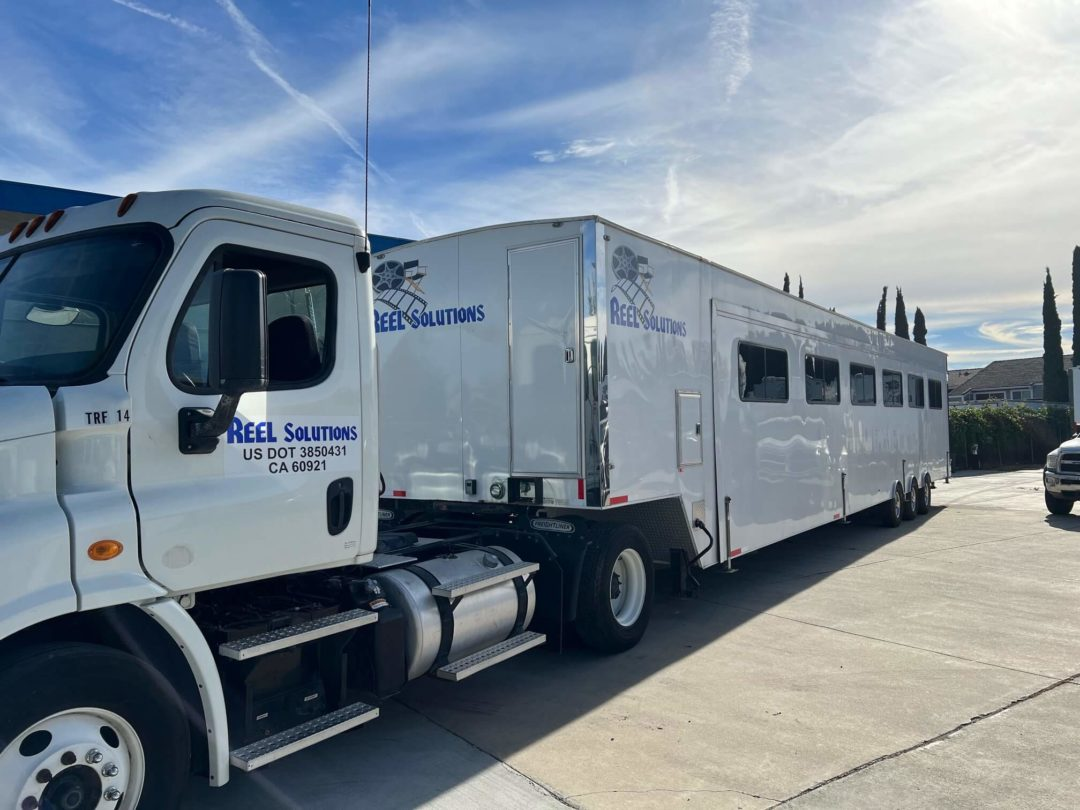 White truck towing a white horse trailer; blue sky.