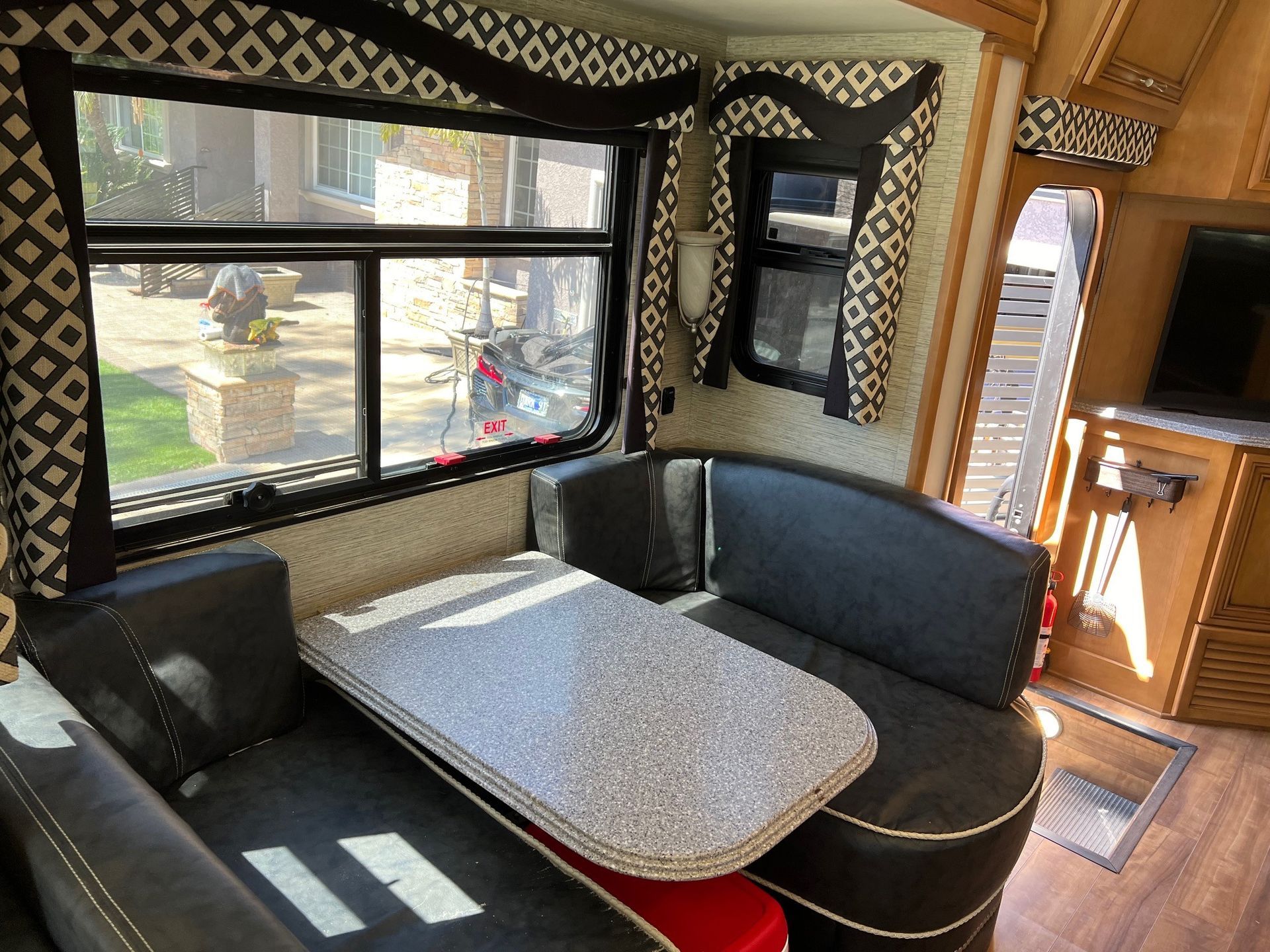 RV interior with a dinette, window, and patterned fabric trim.