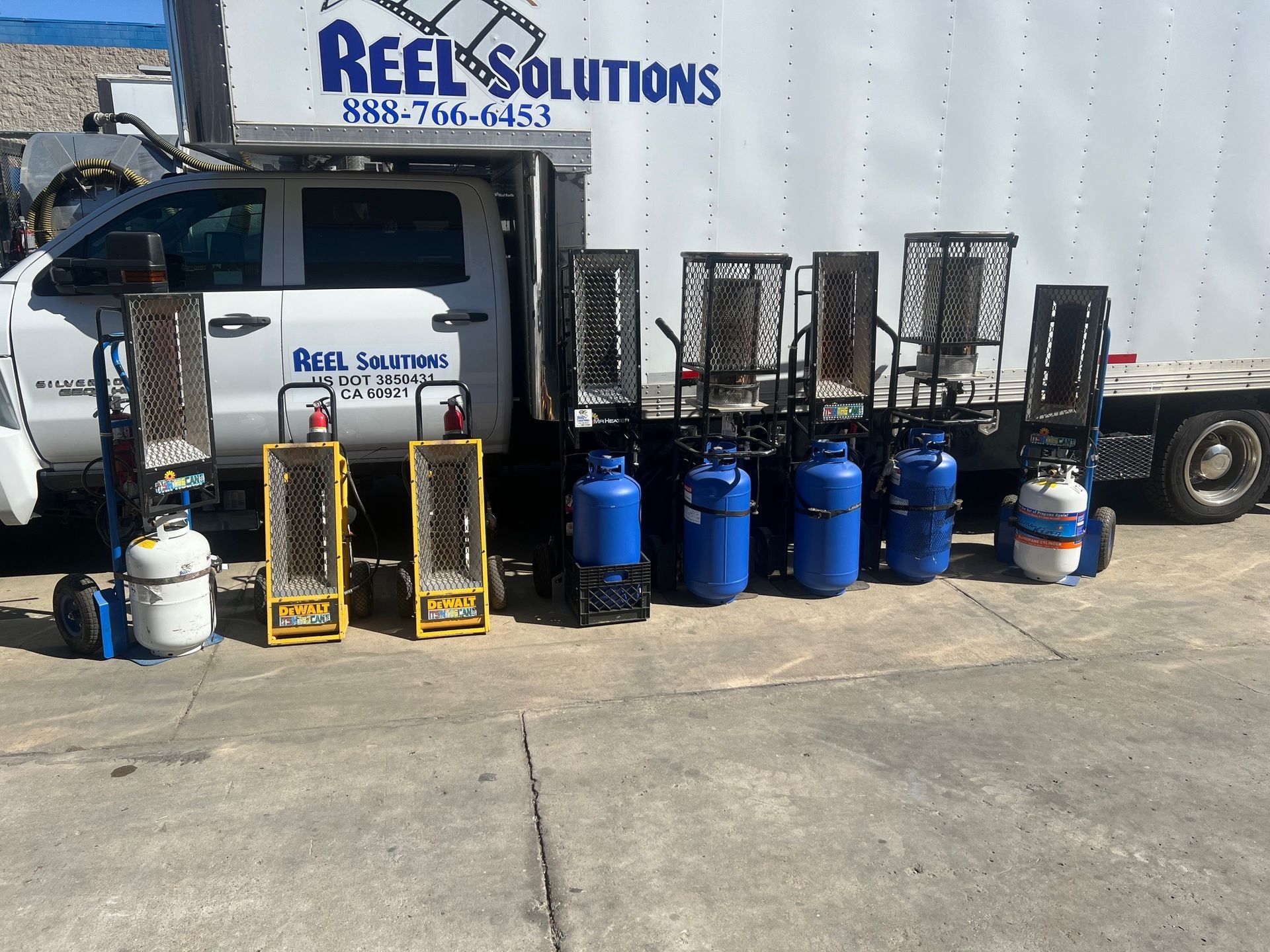 Truck with propane heaters, a blue tank, and a Reel Solutions logo.