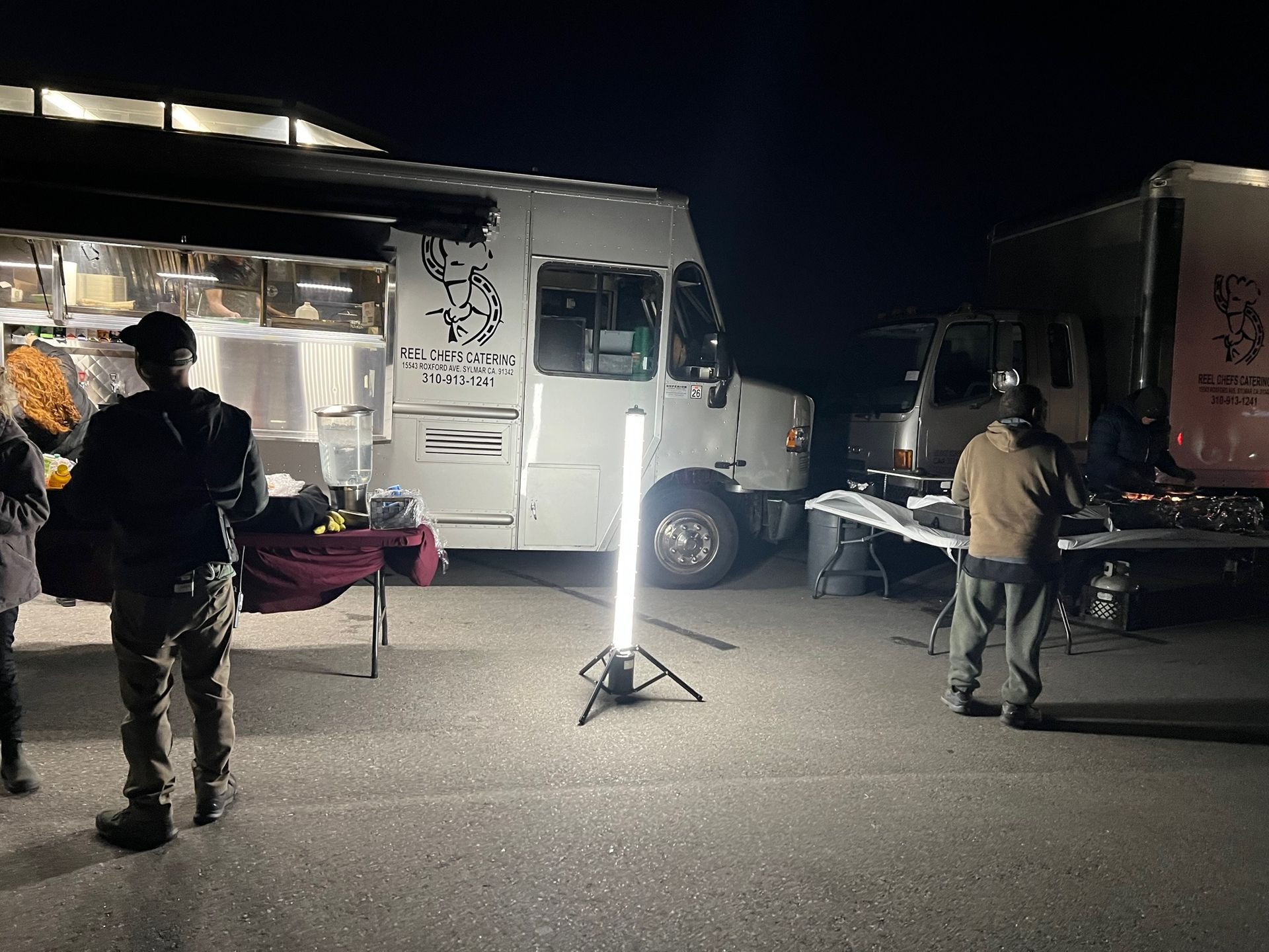 Food trucks at night with people, illuminated by bright lights.