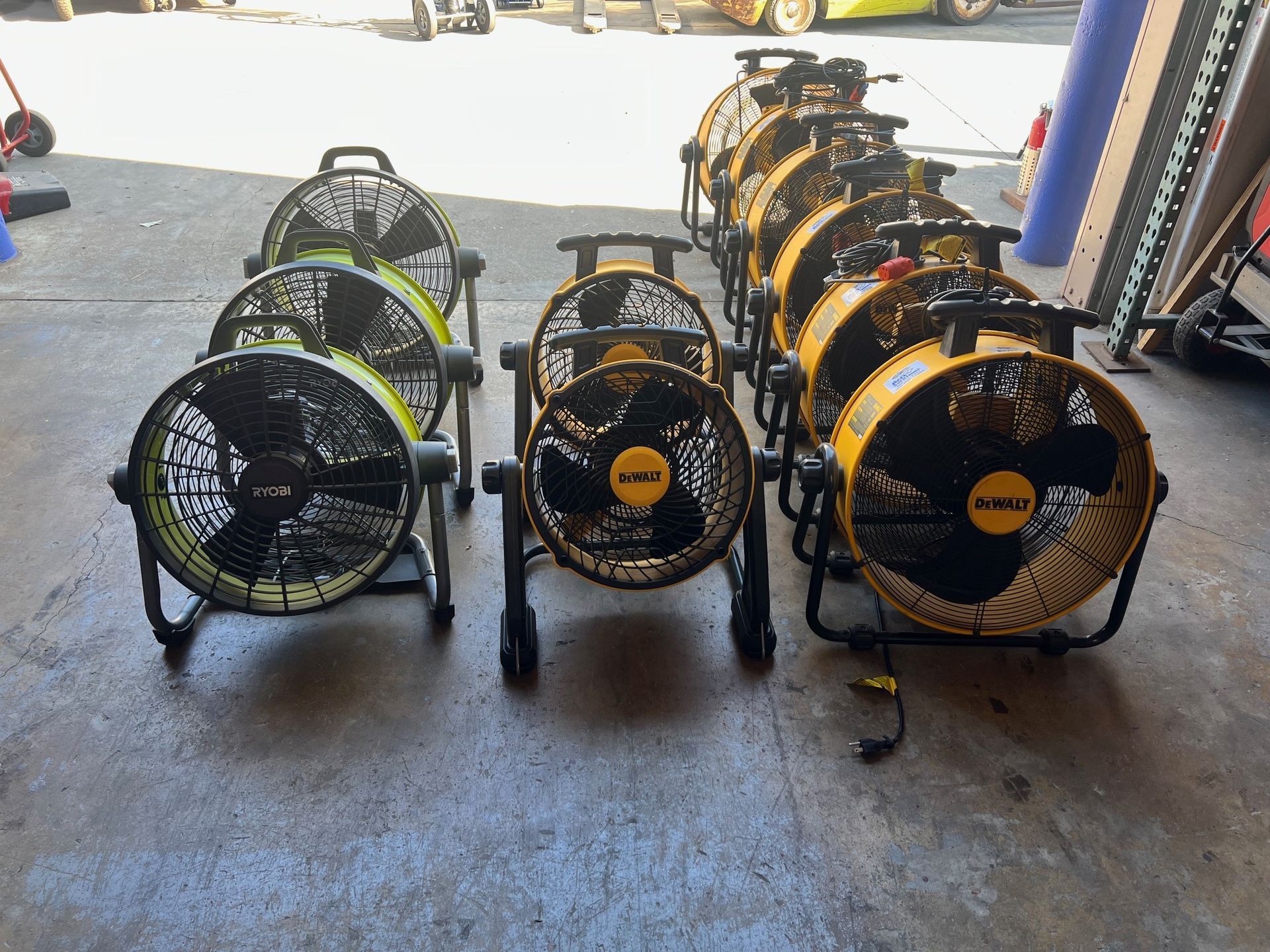 Several large black and yellow fans on a concrete floor, likely for ventilation in a shop.