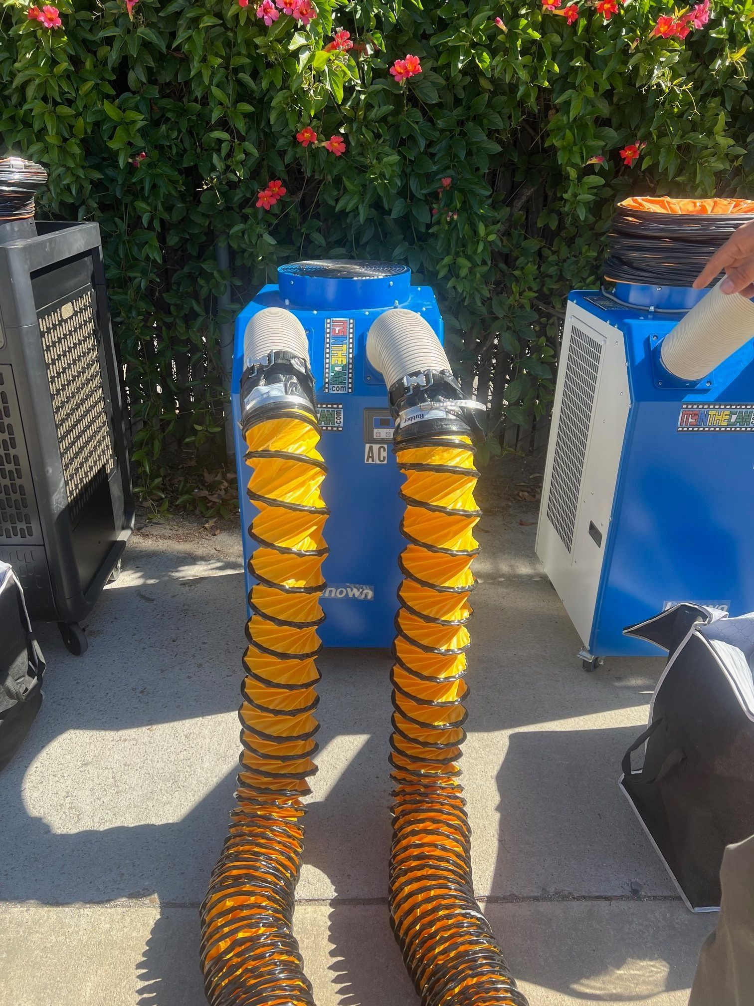 Blue air scrubber with two yellow hoses, outdoors.