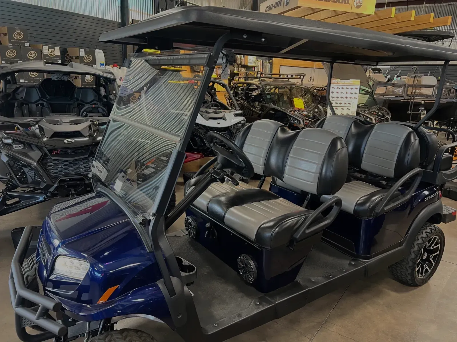 Blue golf cart with black roof and seats; parked indoors.