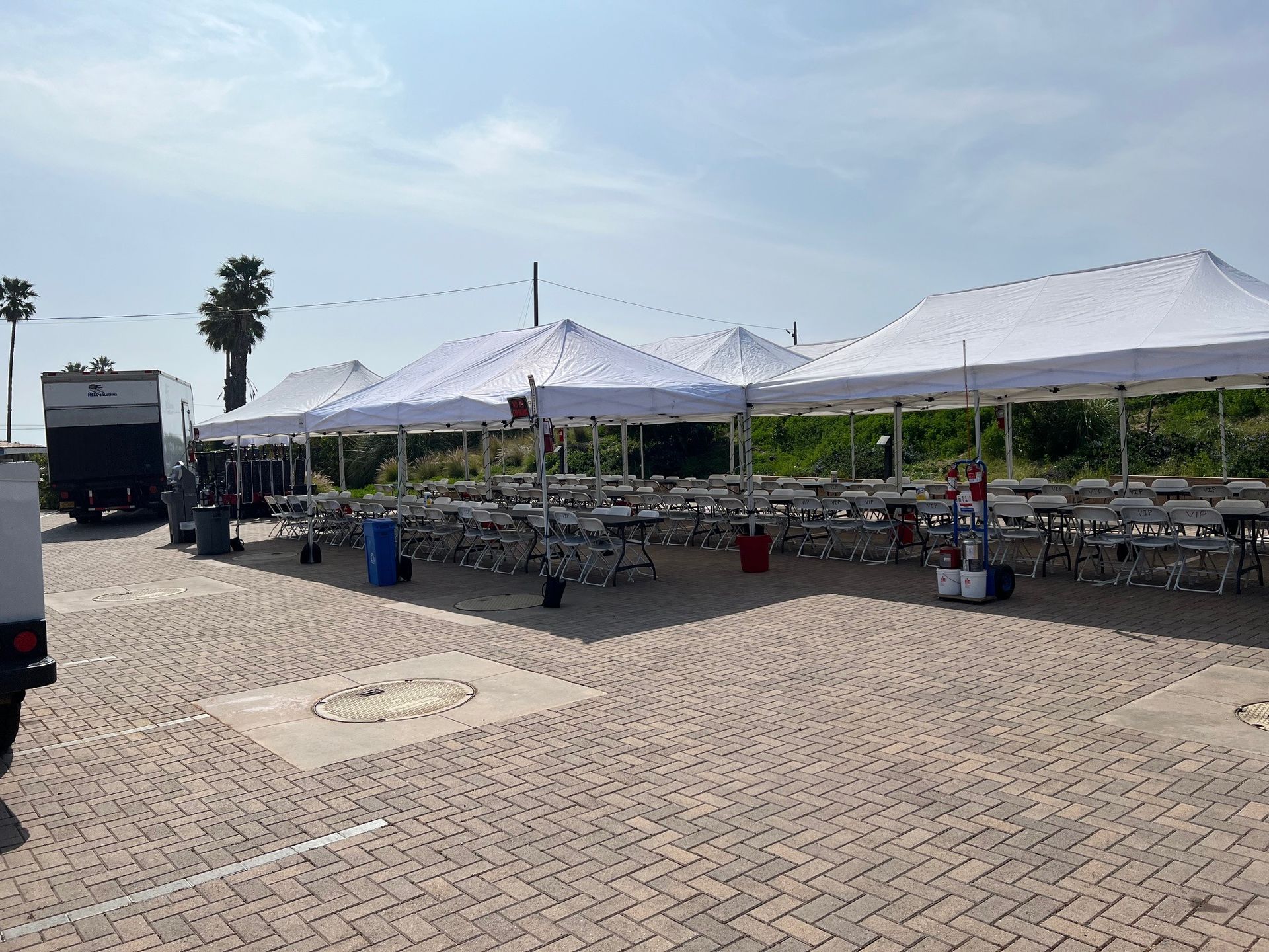 White tents and tables set up in a paved area, likely for an outdoor event.