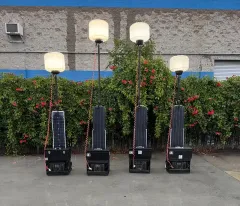 Four portable solar-powered light towers lined up outside, each with a light fixture on a pole.