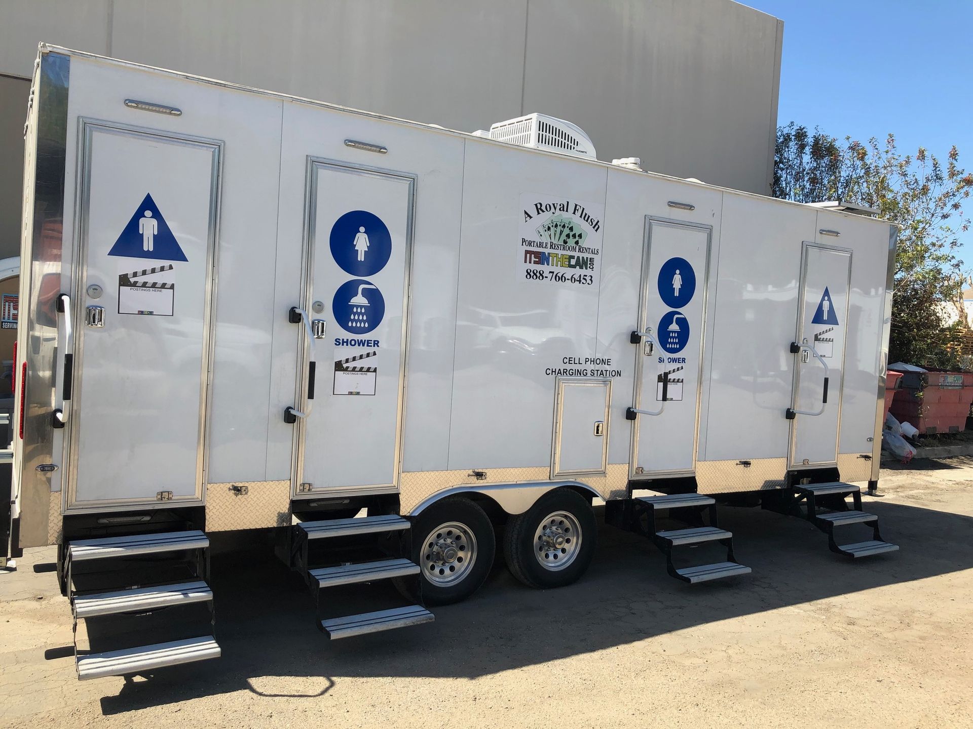 White portable restroom trailer with multiple doors and steps.