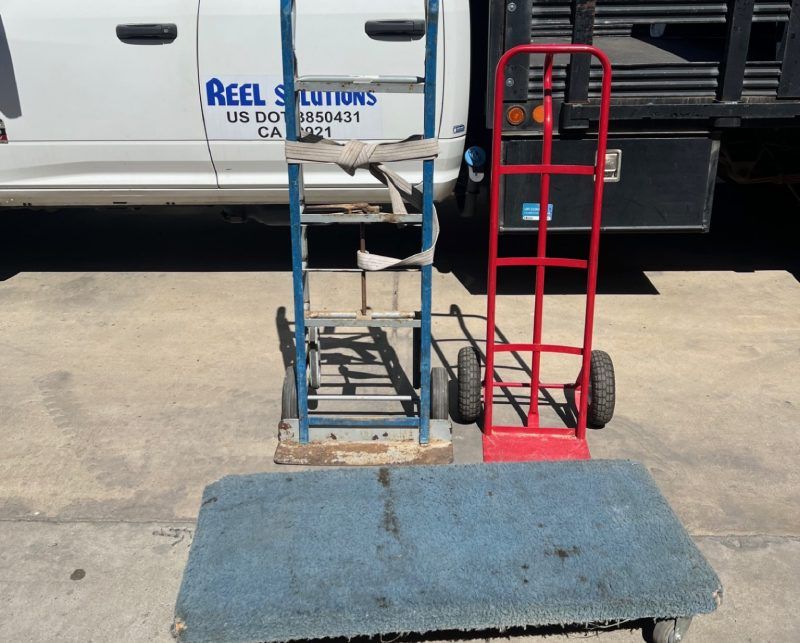 Two hand trucks, one blue and one red, and a blue platform on concrete.