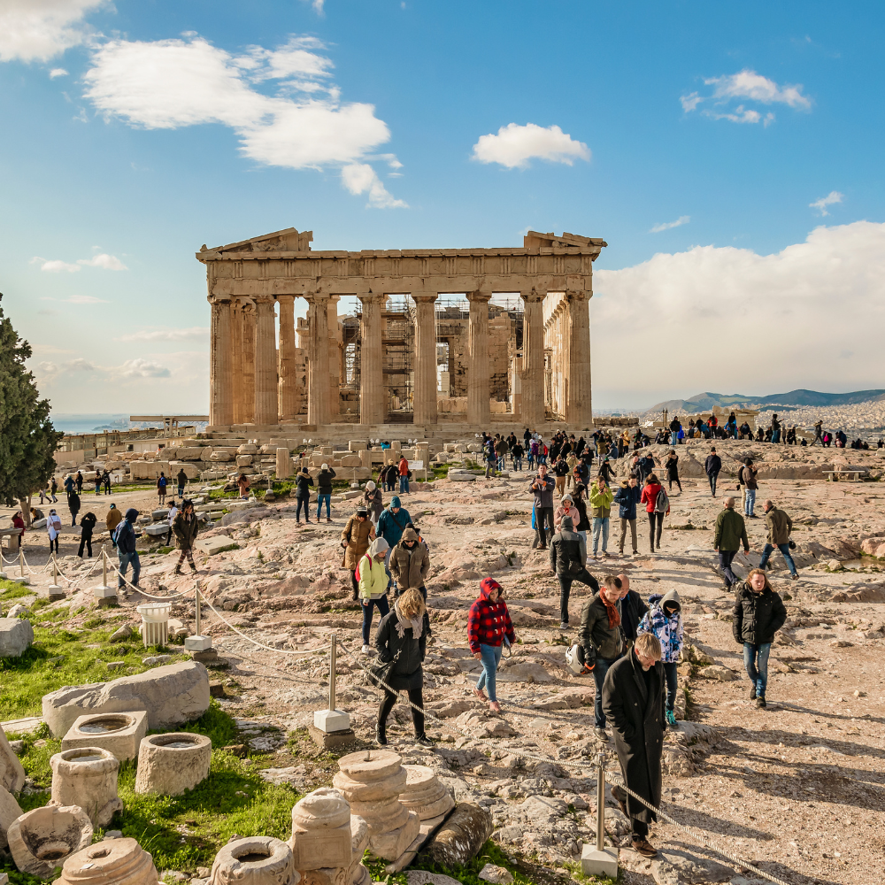 Crowded ruins of the Parthenon on a sunny day with tourists walking among stone remains