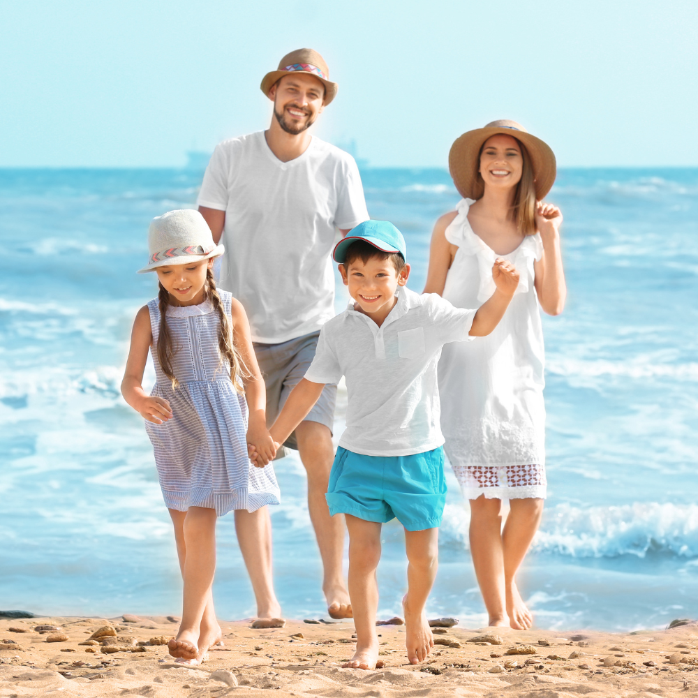 Family walking hand in hand on a sunny beach by turquoise water, smiling and wearing summer clothes