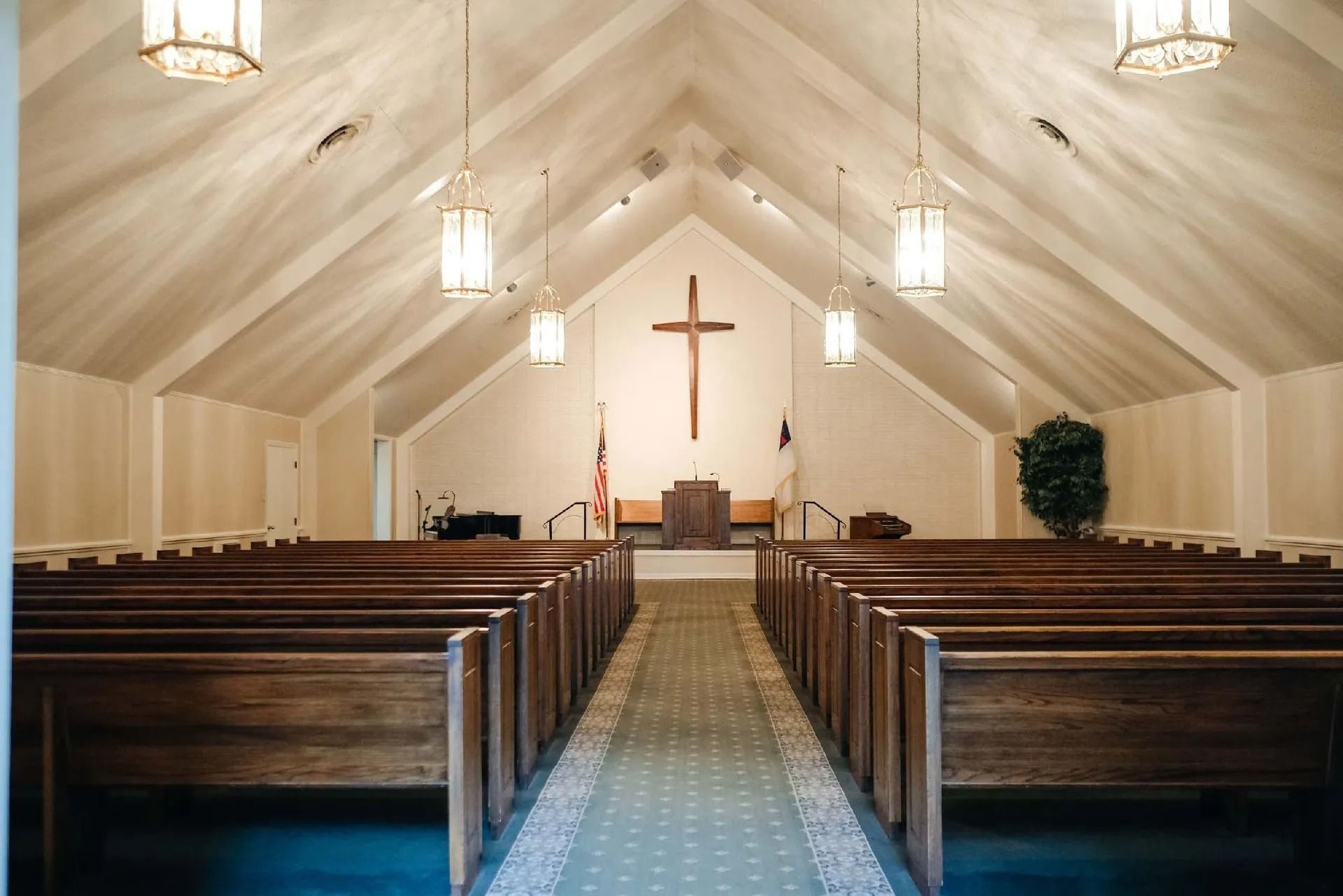 Interior view of a church sanctuary with wooden pews and a cross on the wall.