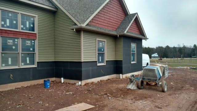 A house under construction with a wheelbarrow in front of it.