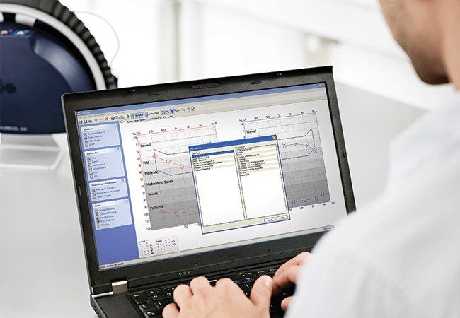 Eine Person benutzt einen Laptop, auf dem eine Audiologie-Software angezeigt wird; 