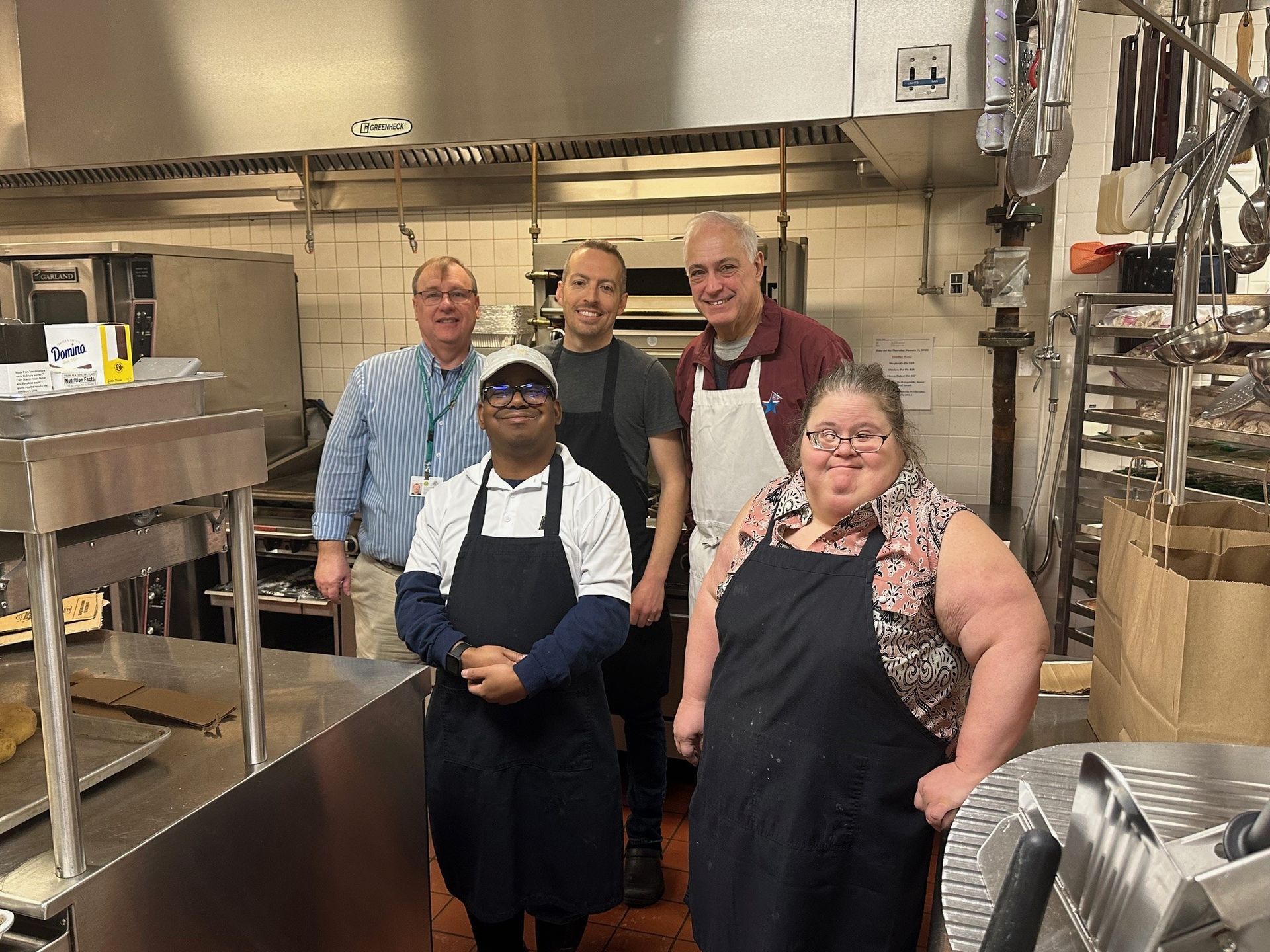 A group of people are standing in a commercial kitchen