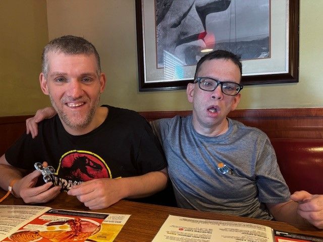 Two men are sitting at a table with a menu in front of them