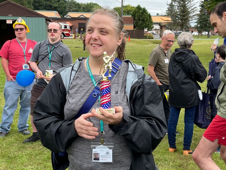 A woman is holding a trophy in her hands in a field.