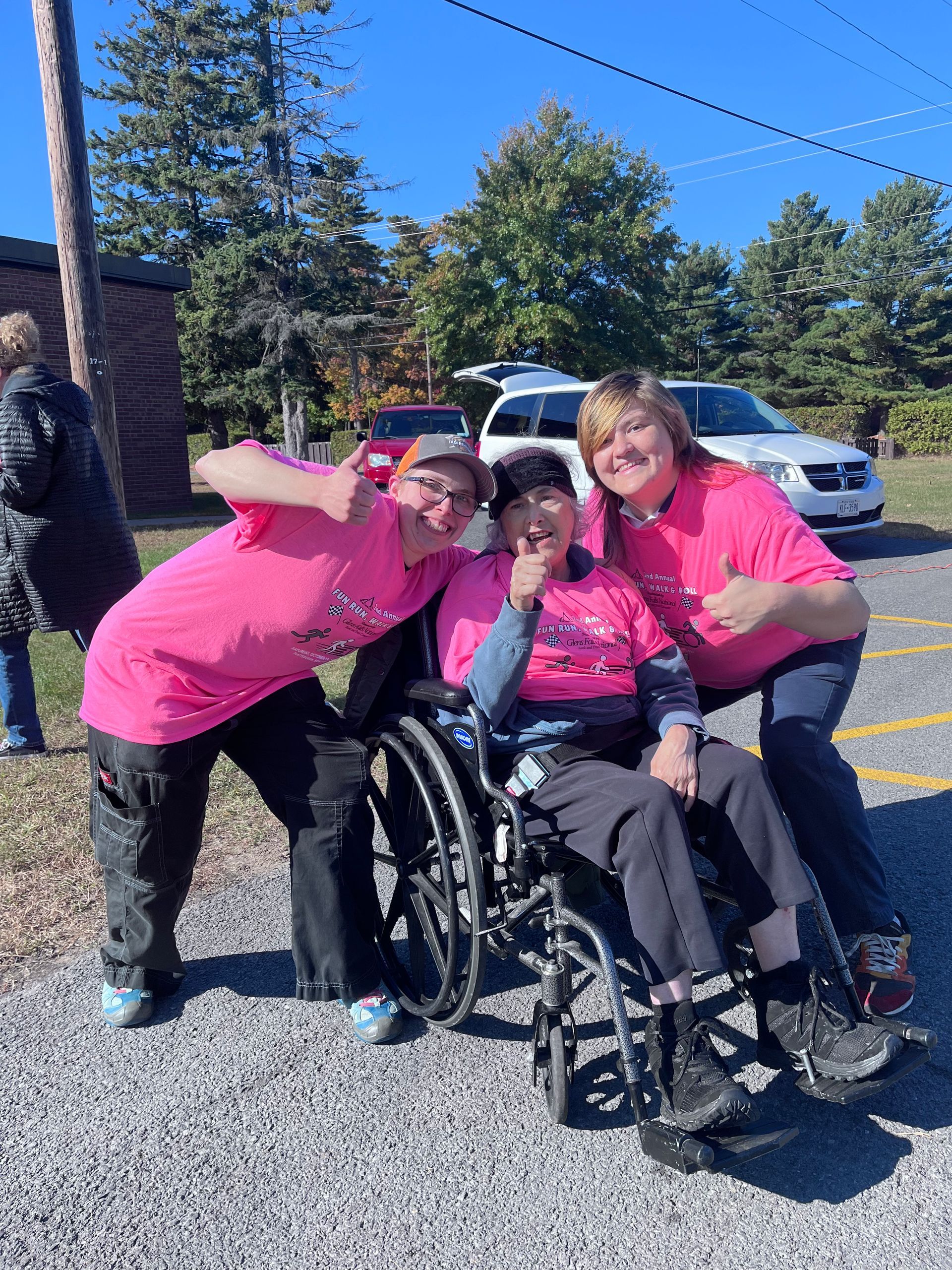 Three women in pink shirts are posing for a picture.