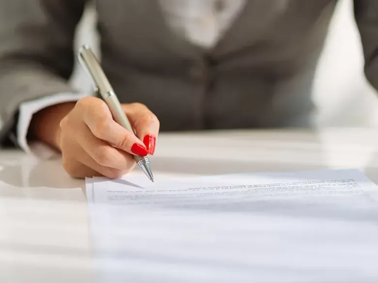 A woman is writing on a piece of paper with a pen.