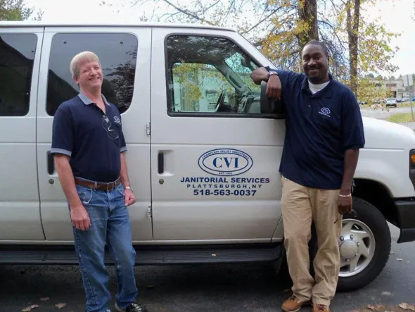 Two men standing next to a van that says cvi.