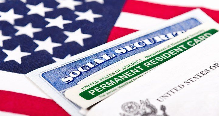 Social security and permanent resident card lay on top of the american flagflag