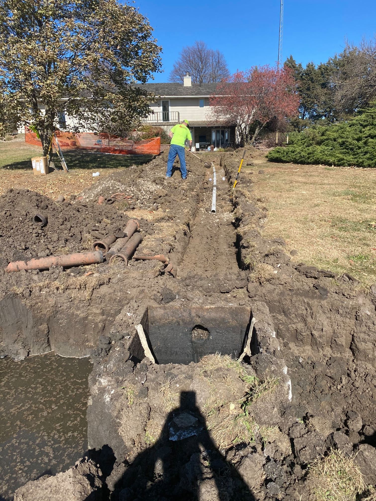 A man is digging a hole in the dirt in front of a house.