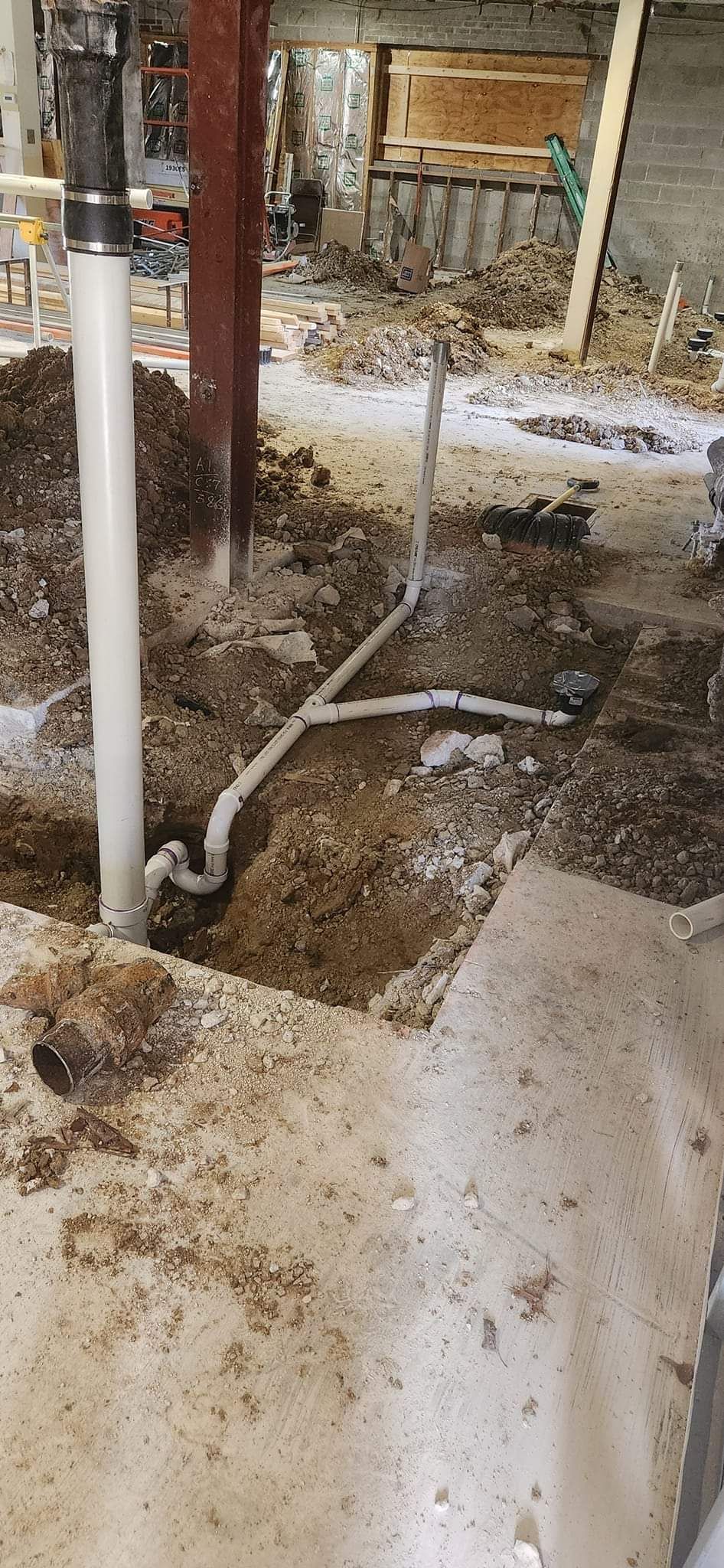 A drain pipe is being installed in a basement.