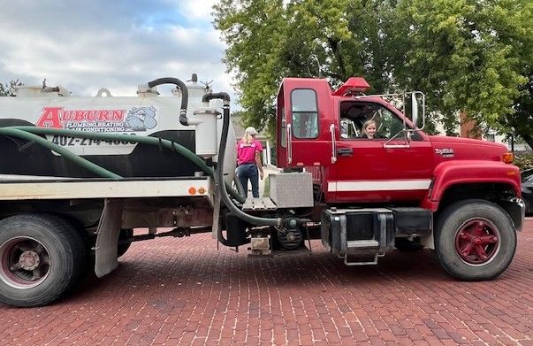A Red Vacuum Truck Is Parked on A Brick Sidewalk.