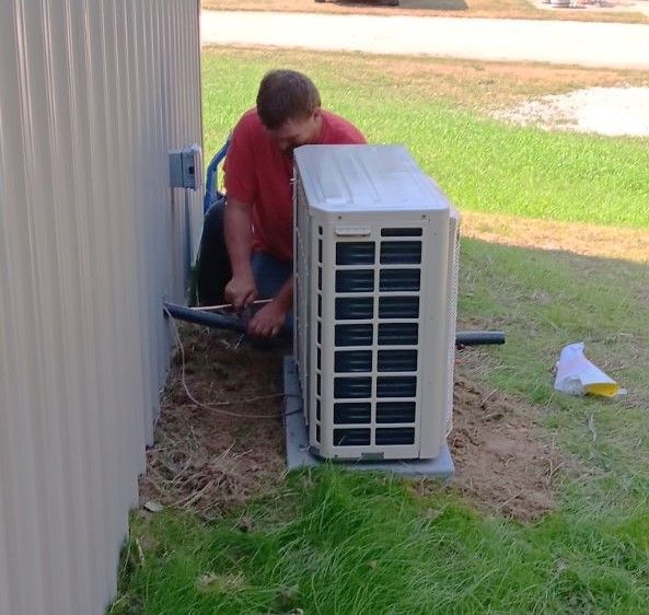 A Man Is Working on An Air Conditioner Outside of A House.