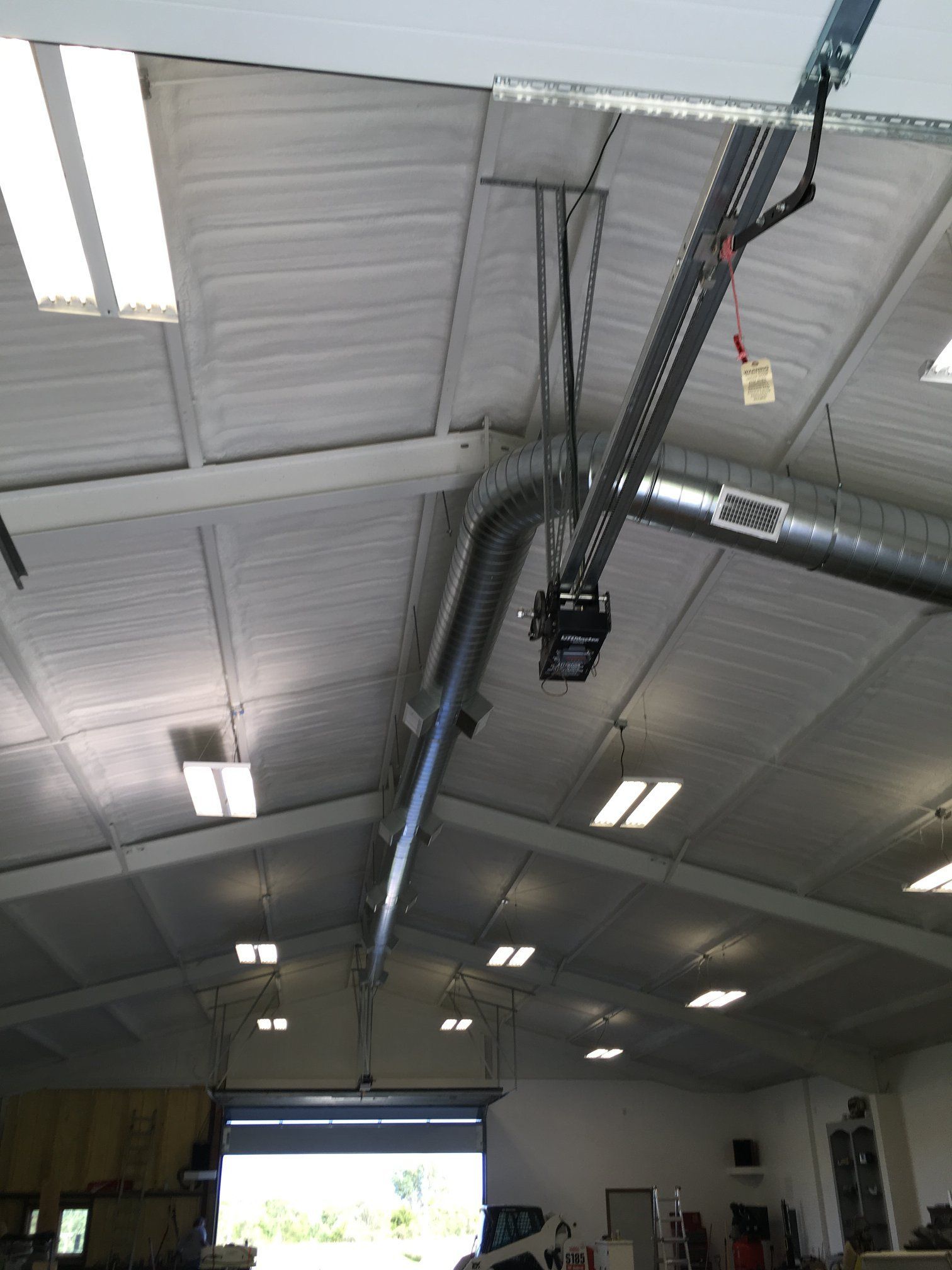 A garage with a garage door open and a ceiling fan.