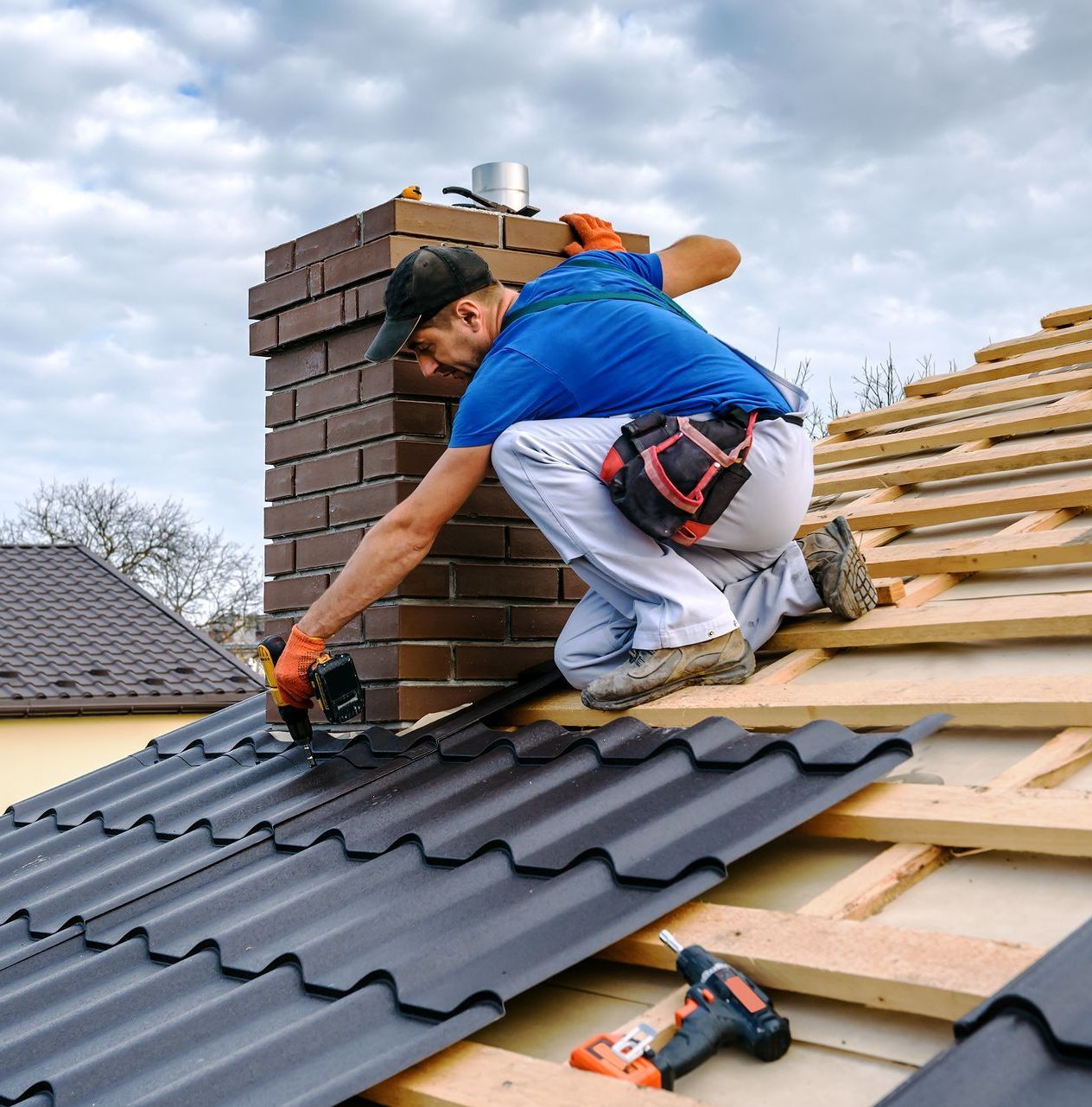 man wearing a blue shirt working on restoring a roof