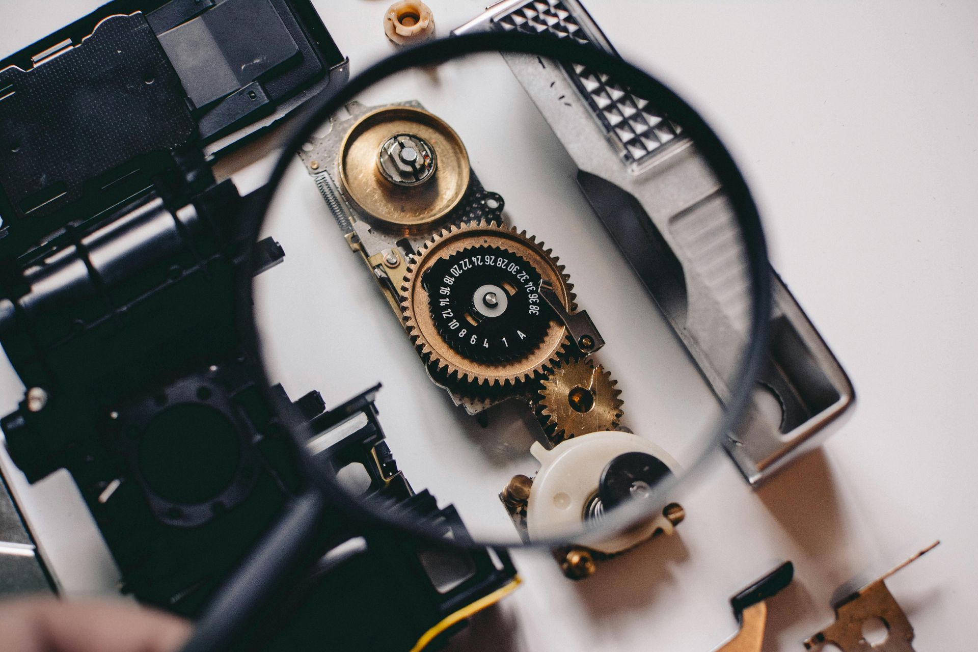 A magnifying glass is being used to look at gears on a table.