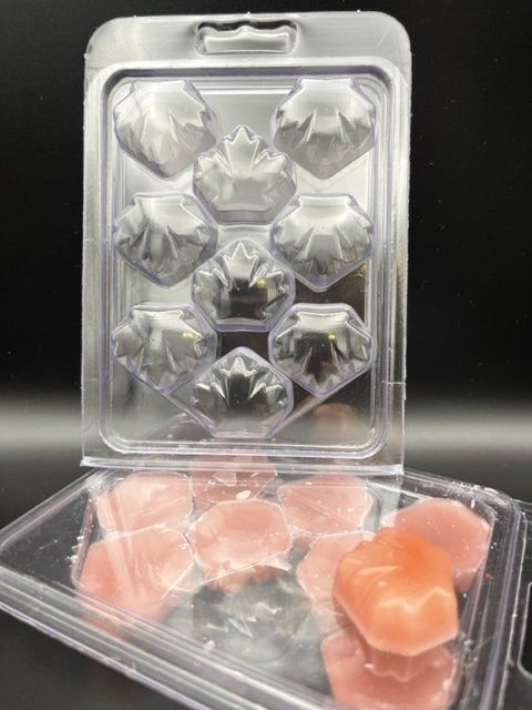 A clear plastic container filled with wax melts on a table.