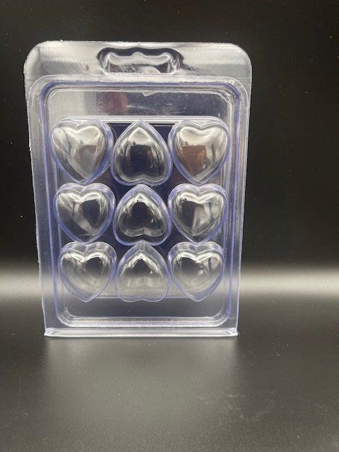 A clear plastic box filled with hearts is sitting on a table.