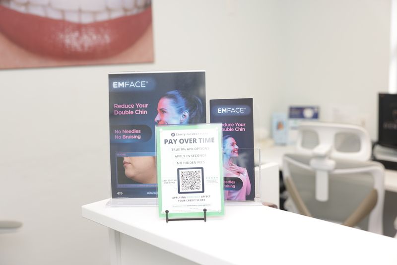 A clinic counter with signs for Emface, a facial treatment, and a QR code for payment.