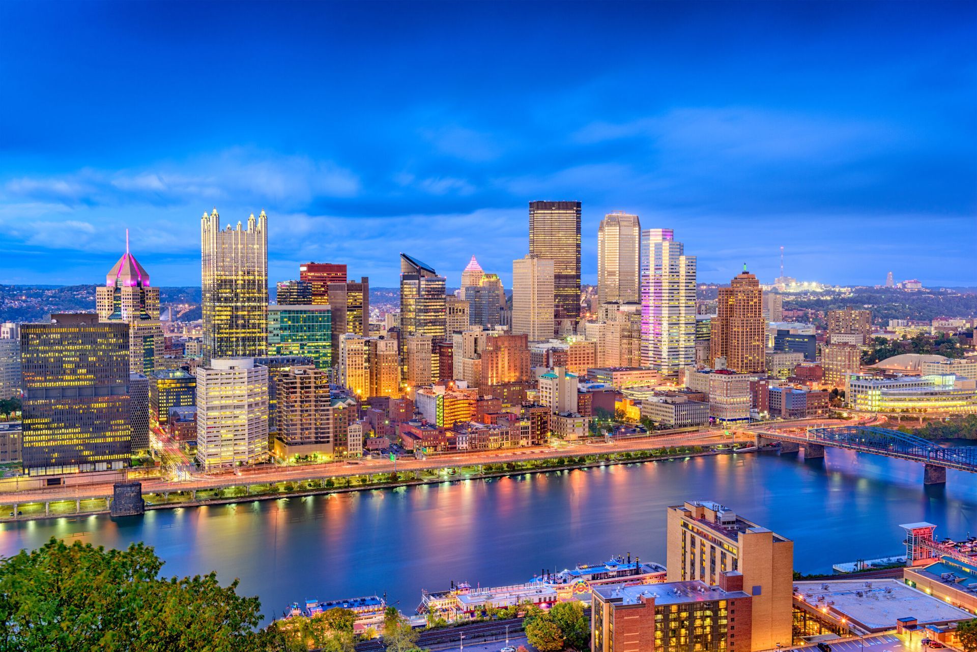 Skyline view of downtown Pittsburgh, Pennsylvania at dusk, with city lights reflecting on the river