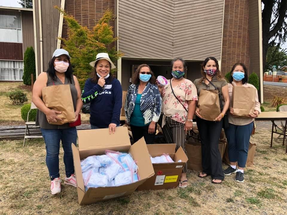 A group of women wearing face masks are standing next to each other in front of a building.