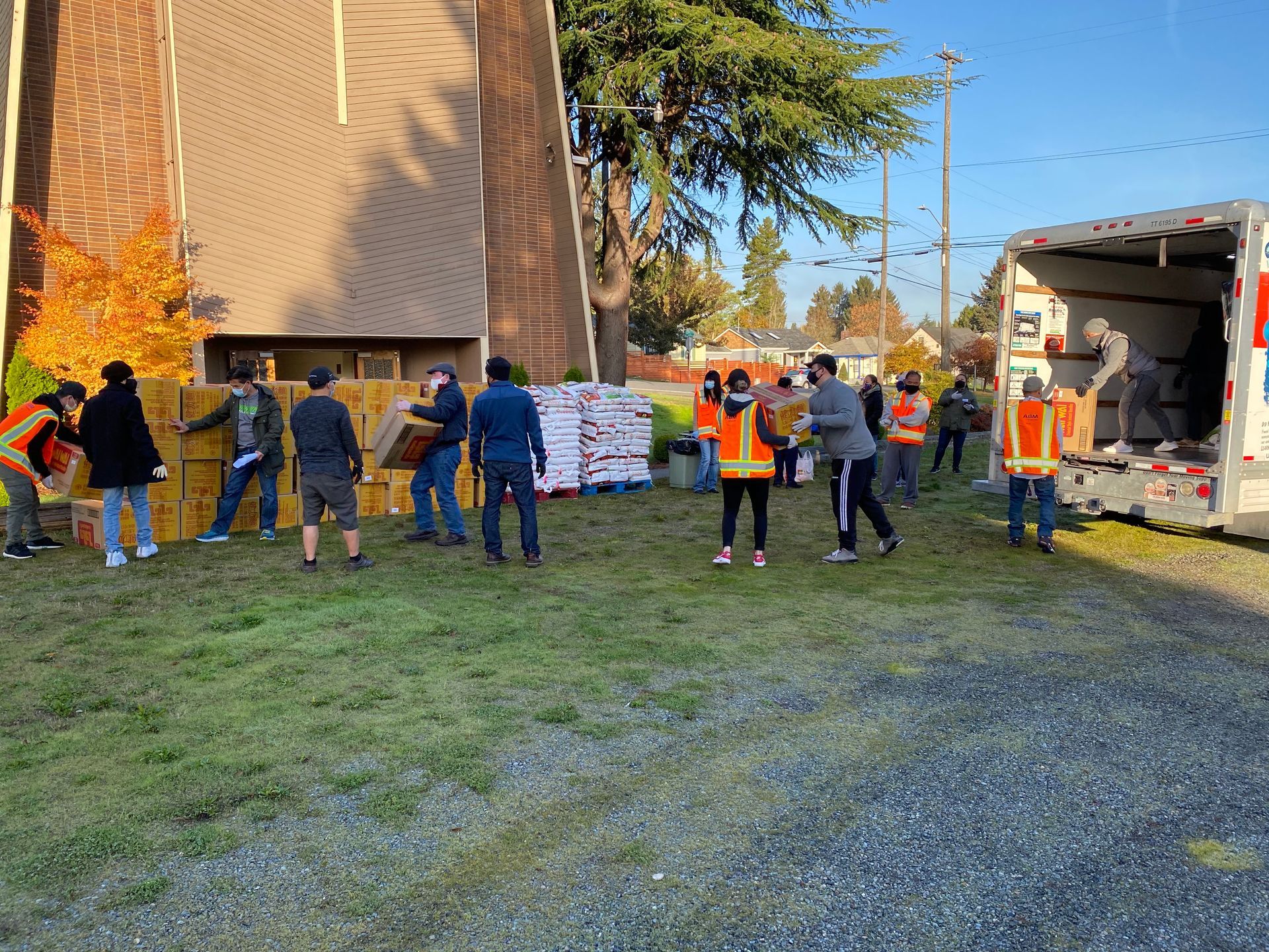 A group of people are standing in a grassy field next to a truck.