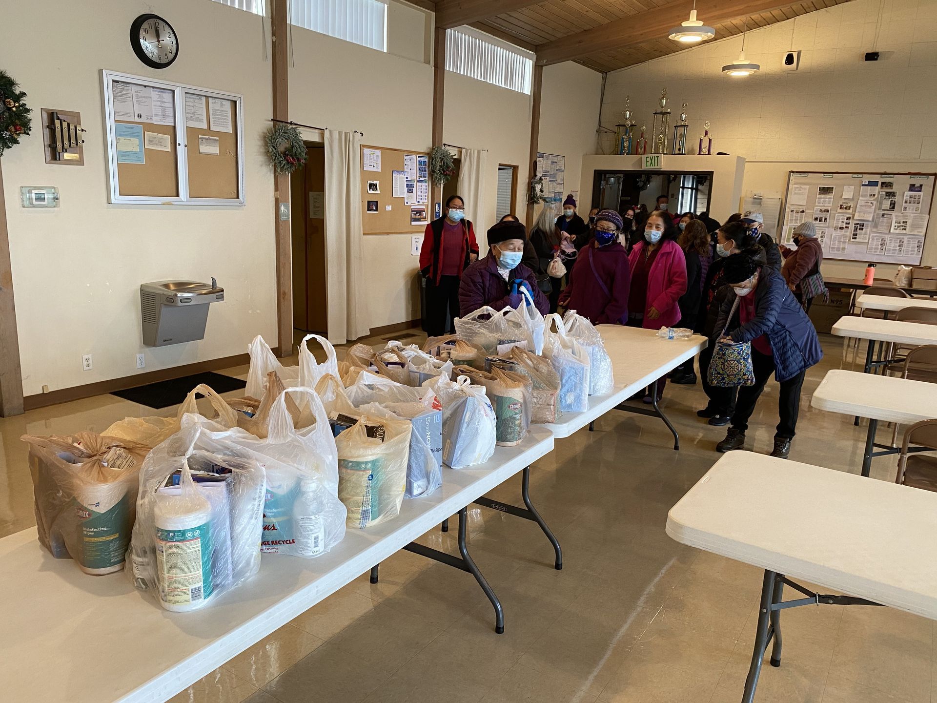 A group of people are standing around a table filled with bags of food.