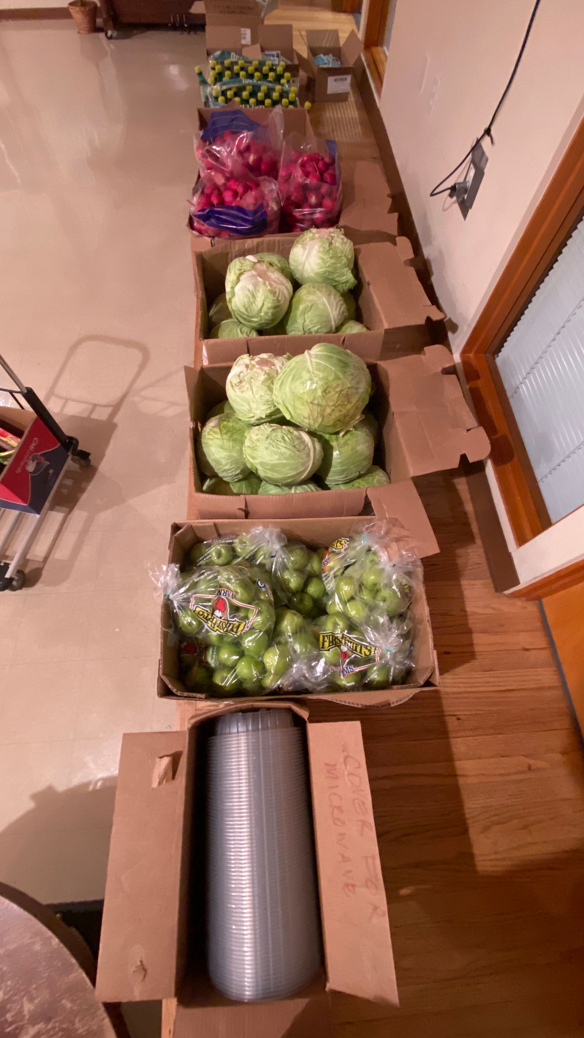 A row of boxes filled with different types of fruits and vegetables.
