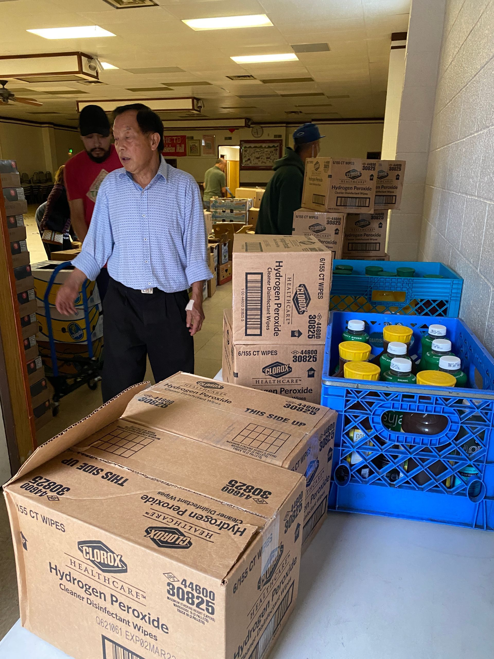 A man is standing in front of a stack of boxes with one that says ' tropicana ' on it
