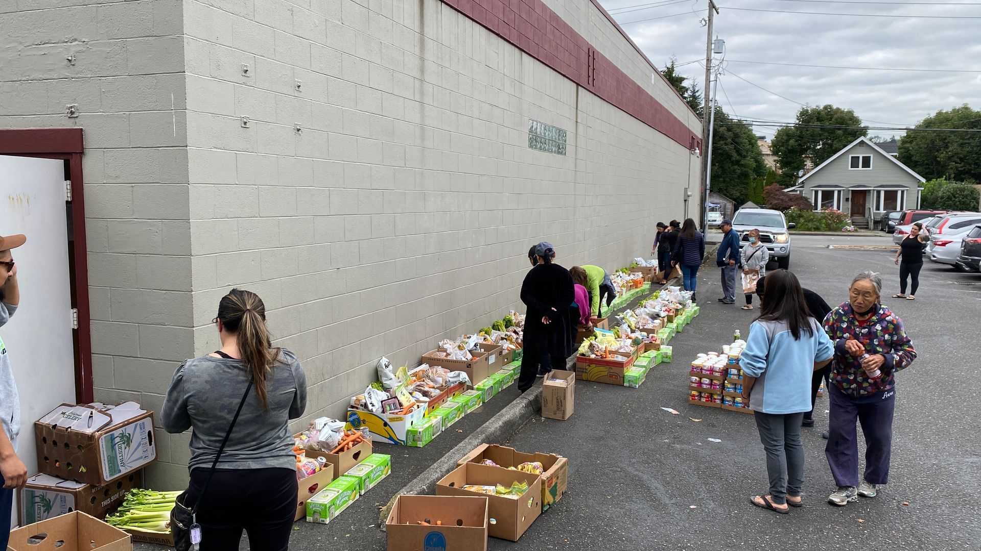 A group of people are standing in front of a building filled with boxes of food.