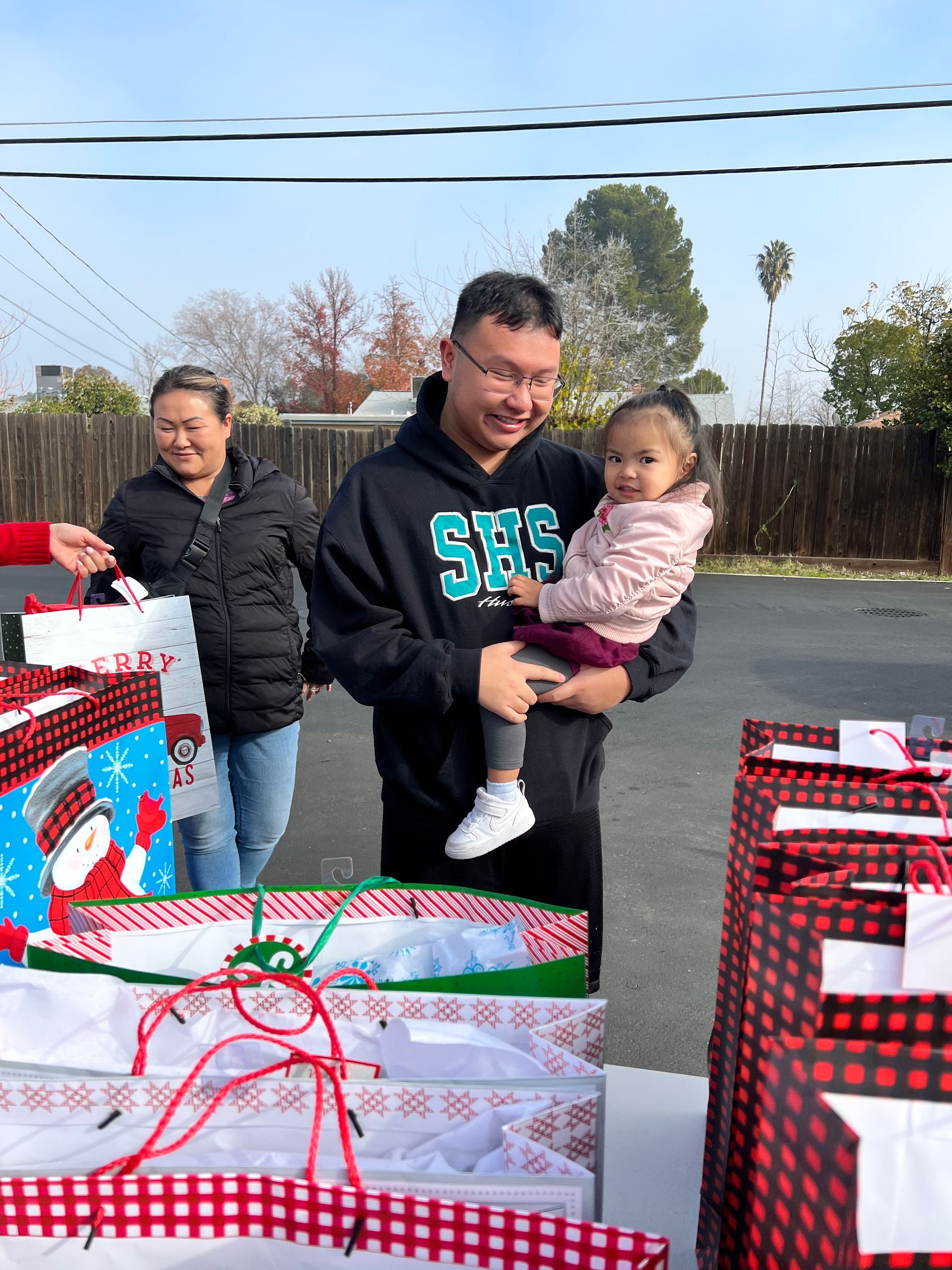 A man is holding a baby in his arms while standing next to a pile of christmas presents.
