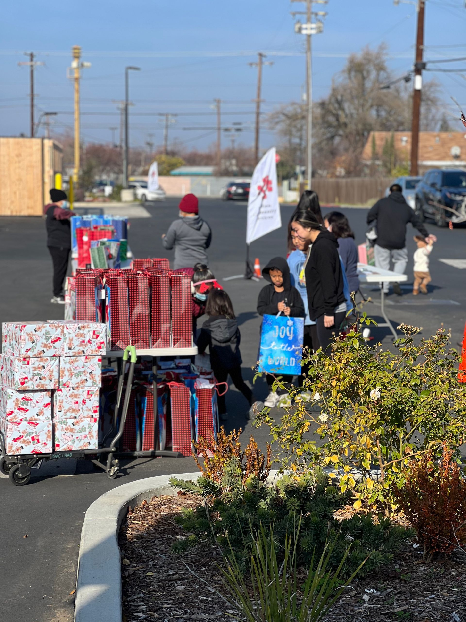 A group of people are standing in a parking lot with boxes of presents.