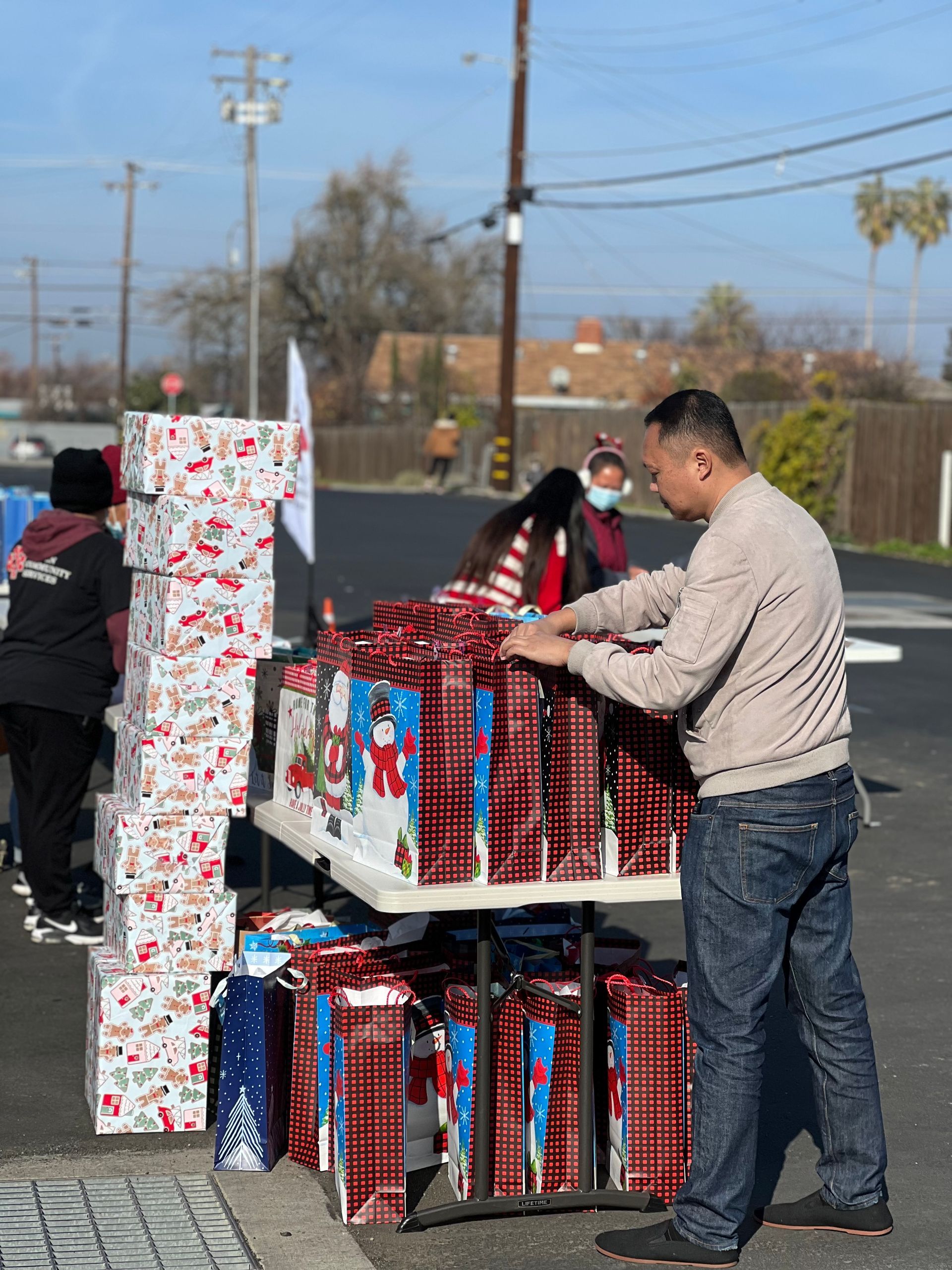 A man is standing in front of a table filled with christmas presents.